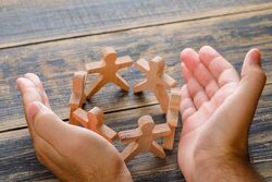 business success concept wooden table top view hands protecting wooden figures people
